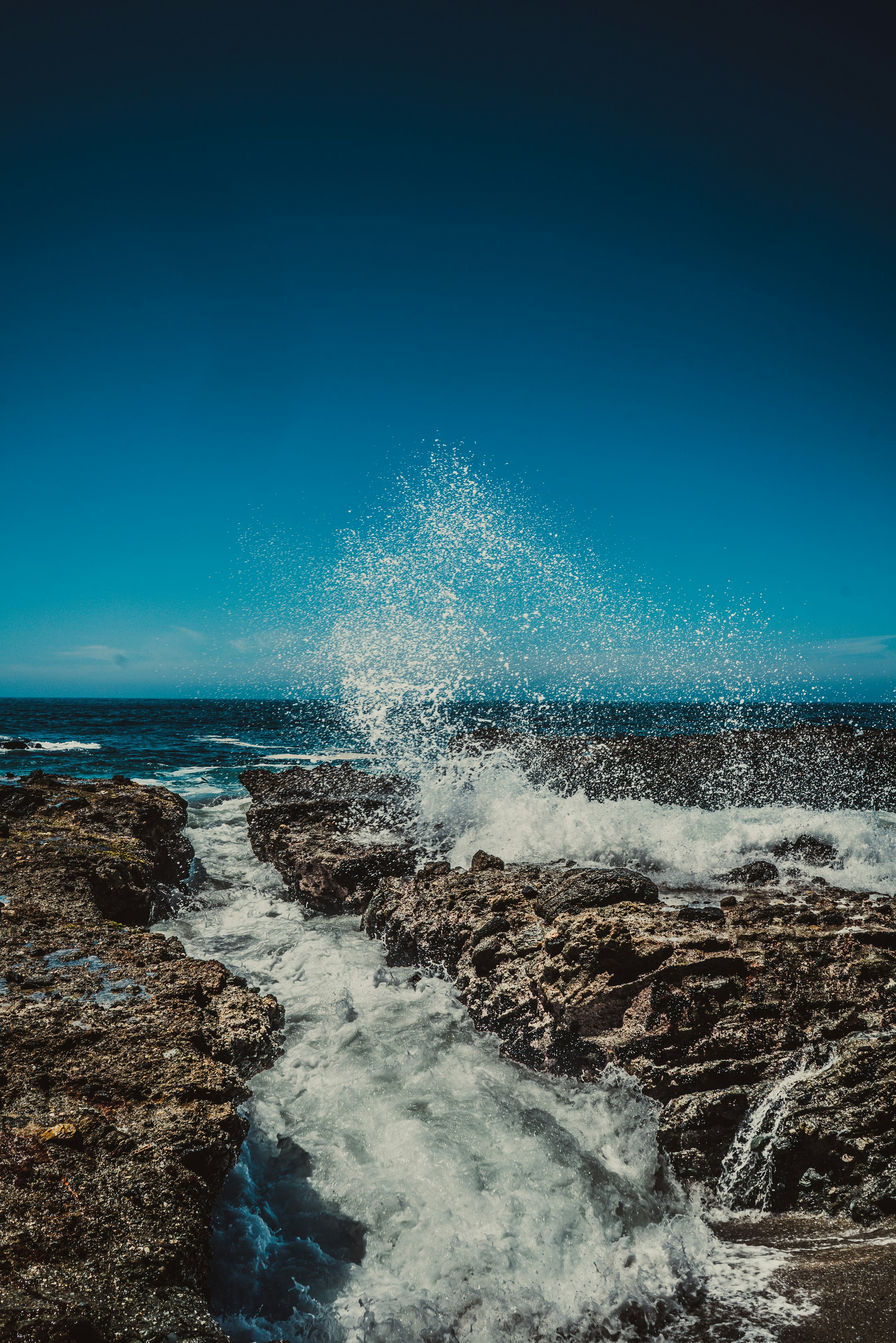 water splashing on rock under blue sky